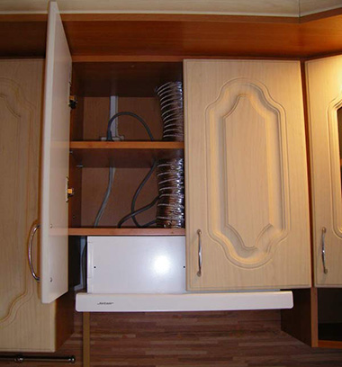 Данная вытяжка встроена в подвесной кухонный модуль и скрывается за его дверками. Чтобы не делать отверстие под вытяжку в нижней полке, ее полностью открутили. Вытяжка прикреплена к средней полочке шкафа саморезами.